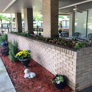 A well-maintained patio area featuring a brick wall with flower pots and decorative landscaping.
