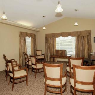 A small, elegantly decorated meeting room with several wooden chairs arranged in a circle.