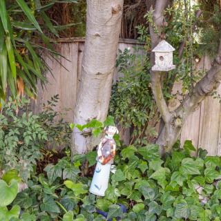 A tranquil garden scene with a birdhouse hanging from a tree surrounded by lush greenery.