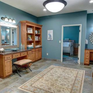 A spacious bathroom with a vanity area, featuring ample storage shelves and soft lighting.