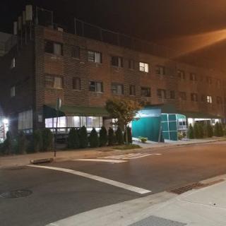 A view of a multi-story brick building at night, illuminated by streetlights.