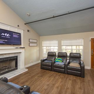 A cozy living room with a home theater setup, featuring recliner chairs and a fireplace.