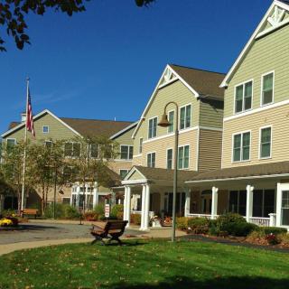 A large residential building with a landscaped lawn and pathway on a clear day.