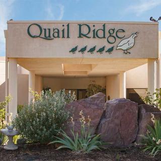 Entrance of the Quail Ridge building with decorative rocks and plants.