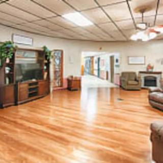 A spacious living room with hardwood flooring, featuring a television, comfortable seating, and a fireplace.