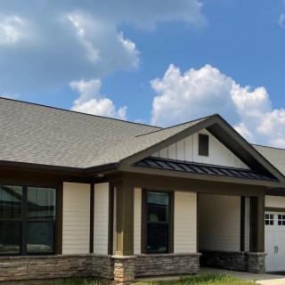 A modern single-story house with a gabled roof under a partly cloudy sky.