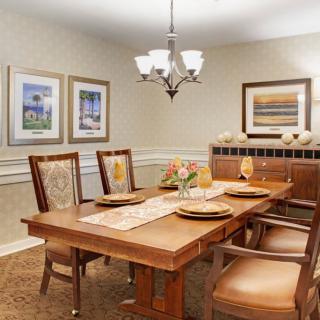 A neatly arranged dining room featuring a wooden table, chairs, and wall art.