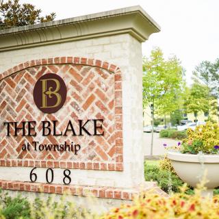 Entrance sign for The Blake at Township surrounded by flowers.