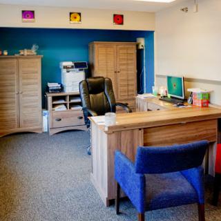 A modern office setup featuring a wooden desk, ergonomic chair, and colorful wall accents.