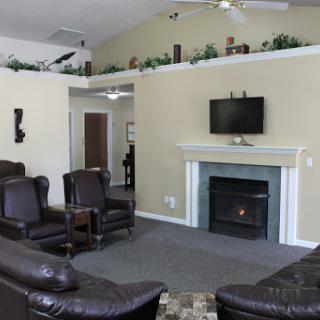 A cozy living room featuring leather chairs, a fireplace, and a mounted TV.
