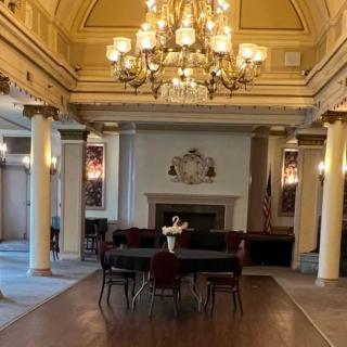 A beautifully designed classic interior featuring a grand chandelier, elegant columns, and a central fireplace.