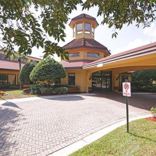 The entrance to a hotel with well-maintained landscaping and a circular driveway.