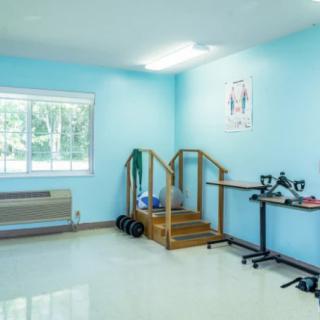 A bright physical therapy room equipped with stairs and various exercise tools.