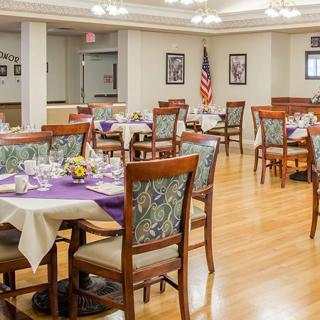 A well-decorated dining room with round tables and chairs, featuring an American flag in the background.