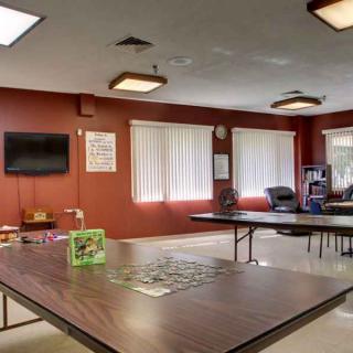 A community center activity room with tables, chairs, and a puzzle in progress.