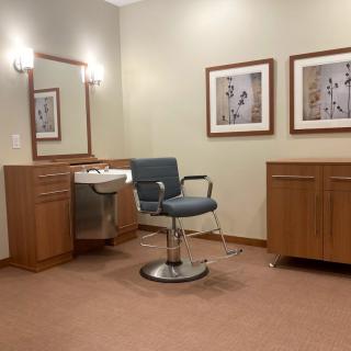 A salon setup with a barber chair, sink, and mirrors.