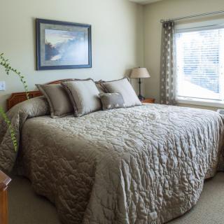 A cozy bedroom with a neatly made bed, adorned with several pillows and soft lighting.