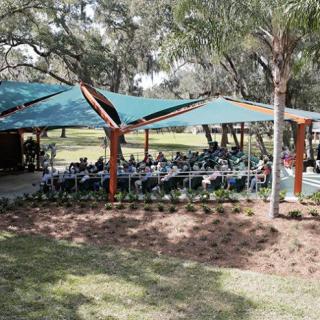 An outdoor event under a canopy in a park setting.