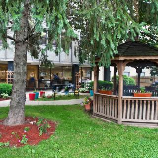 A serene garden with a wooden gazebo and lush greenery.