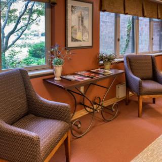 A cozy waiting area with comfortable chairs and a decorative table, featuring a view of the outdoors.