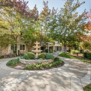 A serene garden featuring a central fountain surrounded by trees and pathways.