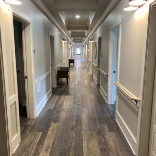 A well-lit hallway with wood flooring and multiple doorways.