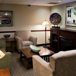 A cozy living room with armchairs and a coffee table, decorated with various artistic pieces.
