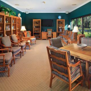 A cozy library reading room with wooden furniture, bookshelves, and natural lighting.