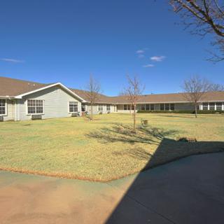 A view of a single-story building with a large lawn and clear blue sky.