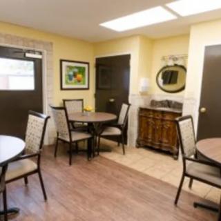 A cozy dining area with round tables and chairs, decorated with artwork and a mirror.