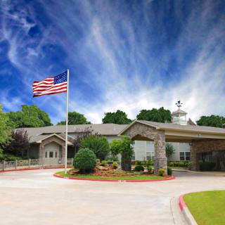A building with an American flag in front, set against a blue sky with wispy clouds.