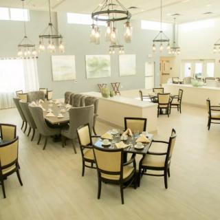 A spacious and elegantly designed dining area with multiple tables, comfortable seating, and decorative chandeliers.