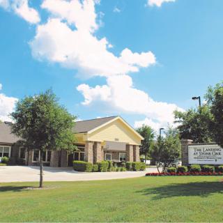 A building with a lawn and a sign under a bright blue sky with clouds.