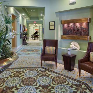 A stylish and welcoming lobby area with seating, plants, and a view of a hallway leading to a piano.