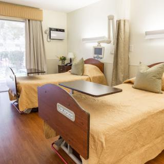 A well-lit and comfortable hospital patient room featuring two adjustable beds.