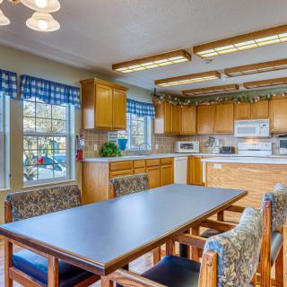 A well-lit kitchen and dining area with wooden cabinets and a central table surrounded by chairs.