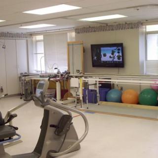 A physical therapy room equipped with exercise machines and fitness balls.