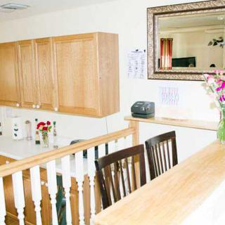 A bright kitchen interior with wooden cabinets, a large mirror, and flowers on the counter.