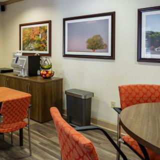 A cozy waiting area with orange chairs, a coffee station, and framed artwork on the walls.