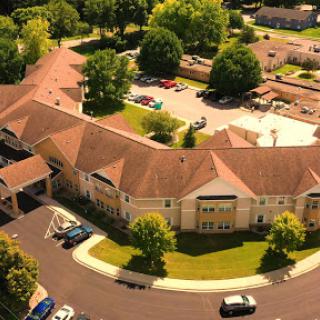 Aerial view of a residential building surrounded by greenery and parking areas.