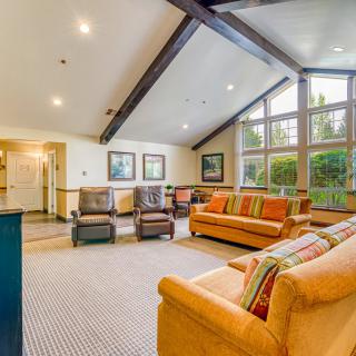 A spacious living room with large windows, featuring comfortable sofas and chairs.