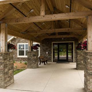 Rustic entrance with stone pillars and a wooden canopy.