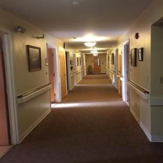 A well-lit indoor hallway with carpeted flooring and doors along both sides.