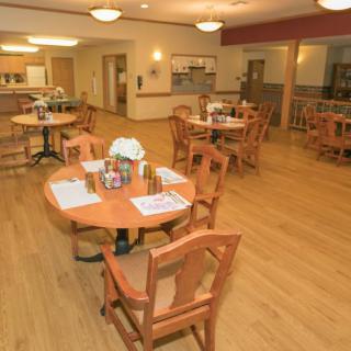 An empty dining area with wooden tables and chairs, featuring soft lighting and a cozy atmosphere.