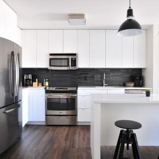 A modern kitchen with white cabinets, stainless steel appliances, and a black backsplash.