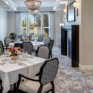 A formal dining room elegantly set up with chandeliers and neatly arranged tables.