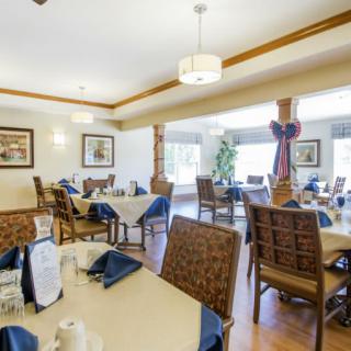 A well-decorated dining room with neatly arranged tables and chairs, featuring elegant lighting and wall art.