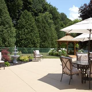 A spacious patio area with outdoor furniture, umbrellas, a gazebo, and lush greenery.