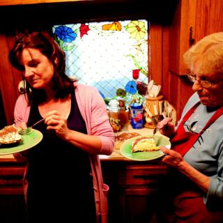 Two women enjoying cake in a cozy kitchen setting.
