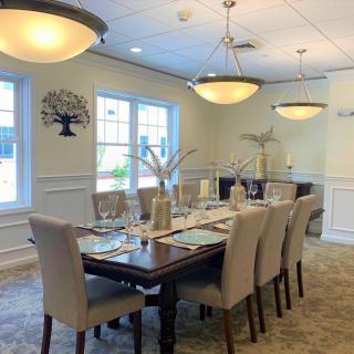 A well-appointed dining room with a large table set for guests, featuring elegant lighting and decor.